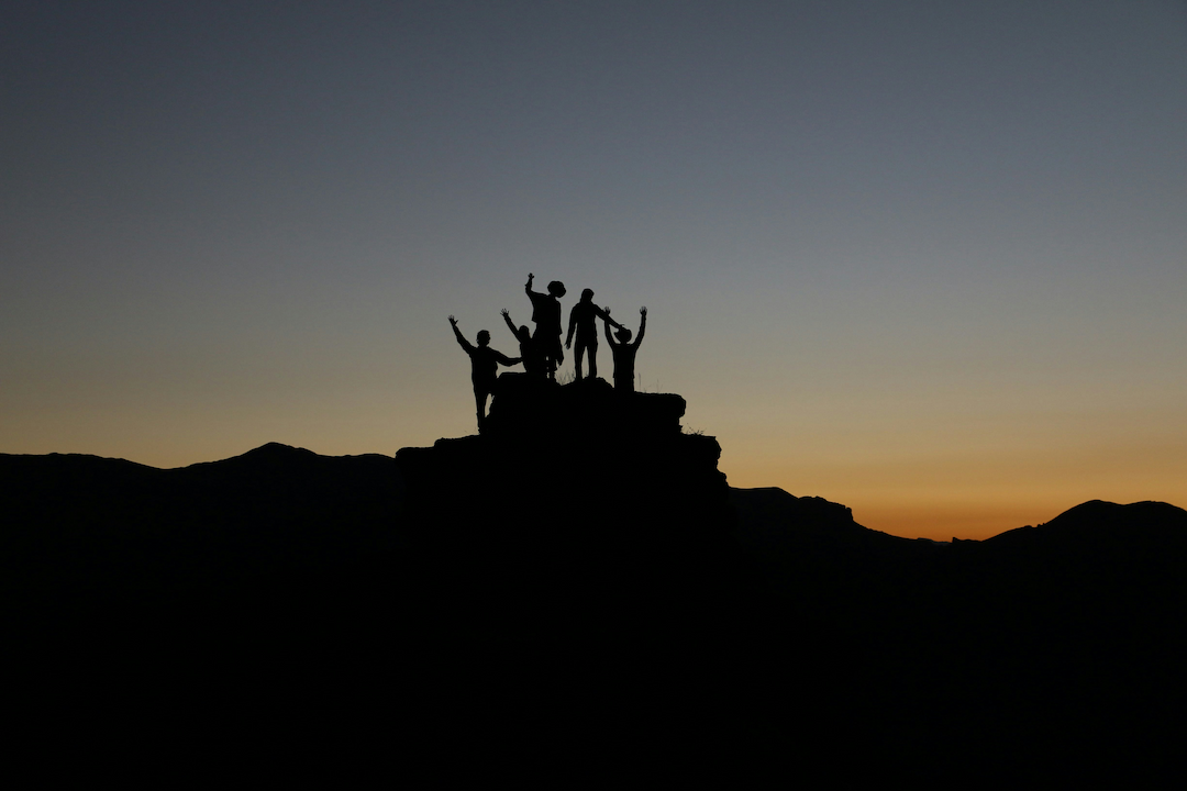 Silhouette of people gathered at the top of a mountain. Photo by Natalie Pedigo on Unsplash.