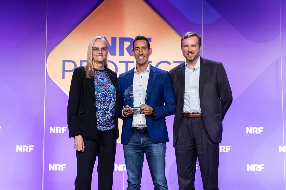 Ulta CISO Diane Brown, Target CISO Rich Agostino, and Christian Beckner of NRF photographed together on a stage against a purple background that, reads “NRF Protect” with Rich Agostino holding a crystal award